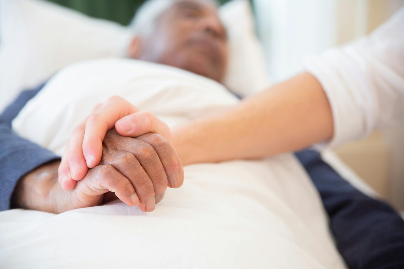 Care - elderly man in bed with hand holding